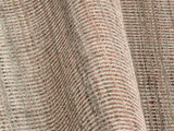 Nahaufnahme eines Designer Teppichs mit einem geometrischen Muster in Beige- und Brauntönen, perspektivisch von der Seite aufgenommen.