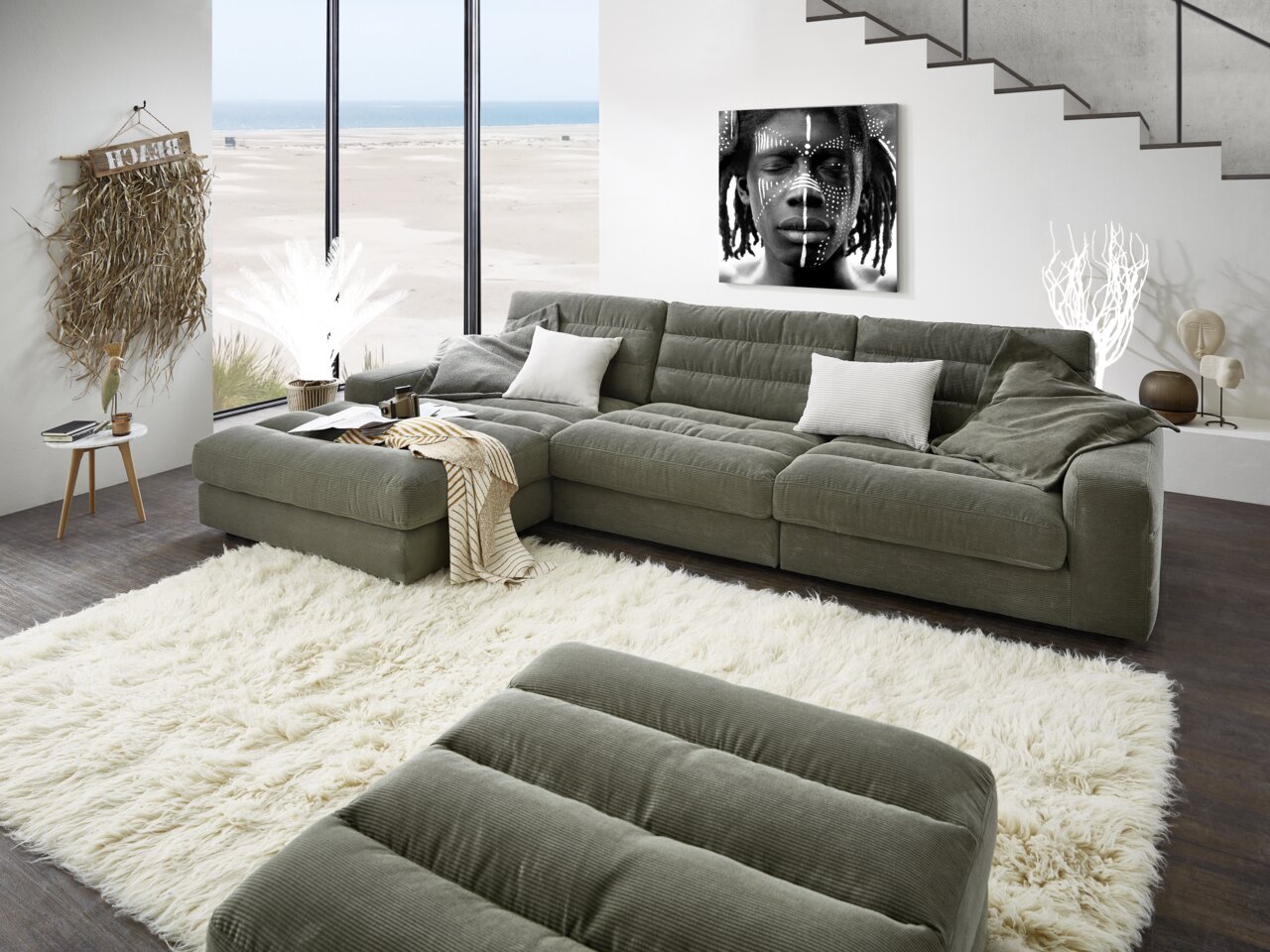 Gezellige set met ligstoelen in een moderne woonkamer met uitzicht op het strand door de grote ramen.