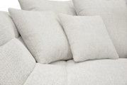 Nahaufnahme eines hellbeigen, weich gepolsterten Sofas mit strukturiertem Stoffbezug und mehreren Kissen, Perspektive: leicht von vorne/seitlich
