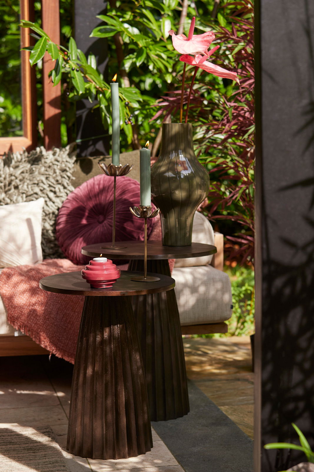 Light&Living Kissen BEREND Gemütliche Gartenszene mit einem runden, lila Kissen auf einem Sofa, umgeben von grünen Pflanzen. Perspektive von vorne.