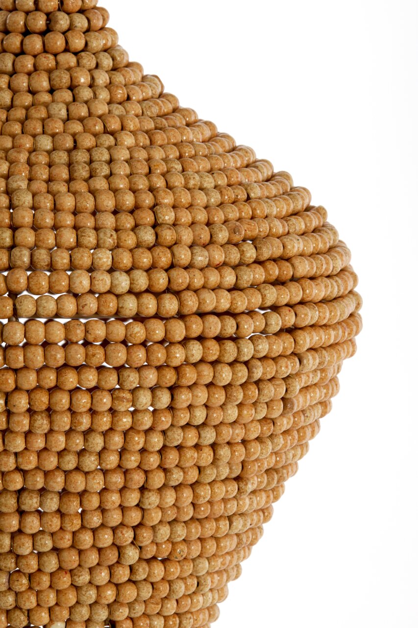 Close-up van een hanglamp met ronde, houtkleurige kralen, gezien vanuit een zijaanzicht.