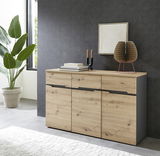 Modernes Sideboard aus Holz mit drei Schubladen und drei Türen, dekoriert mit Büchern, Kerzen und einer Skulptur, seitliche Perspektive.