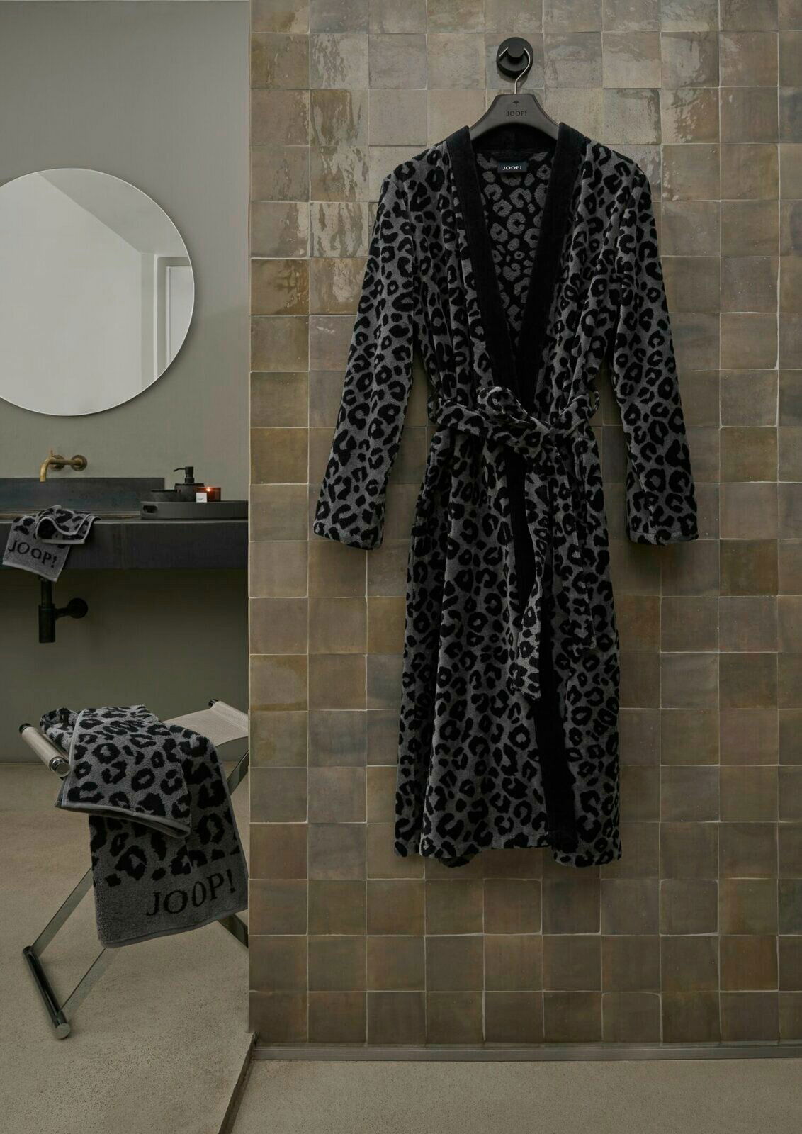 Leopardengemusterter Bademantel in einem modernen Badezimmer, frontal an einer Wand aufgehängt.