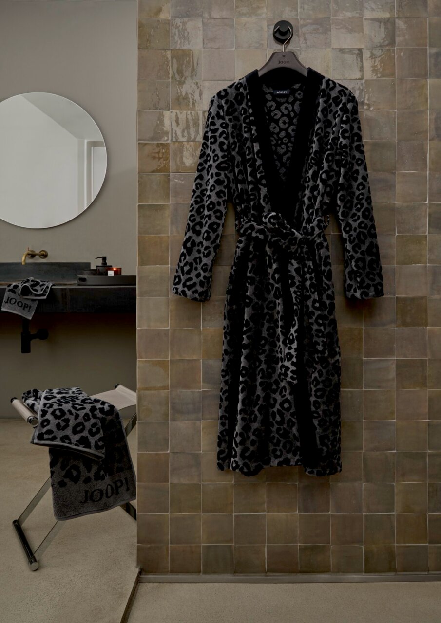 Leopardengemusterter Bademantel in einem modernen Badezimmer, frontal an einer Wand aufgehängt.