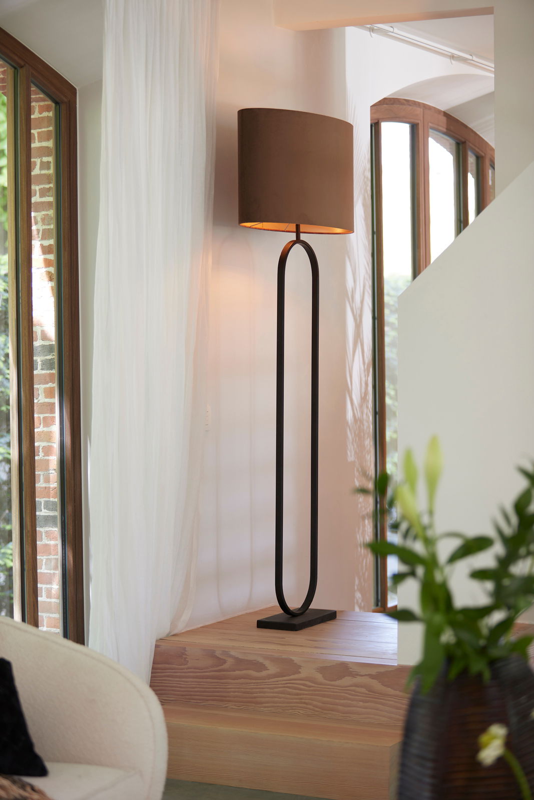 Light&Living Stehleuchte JAMIRI Moderne Stehleuchte mit ovalem, schwarzem Gestell und braunem Lampenschirm, seitliche Perspektive in einem stilvollen Raum mit großen Fenstern.