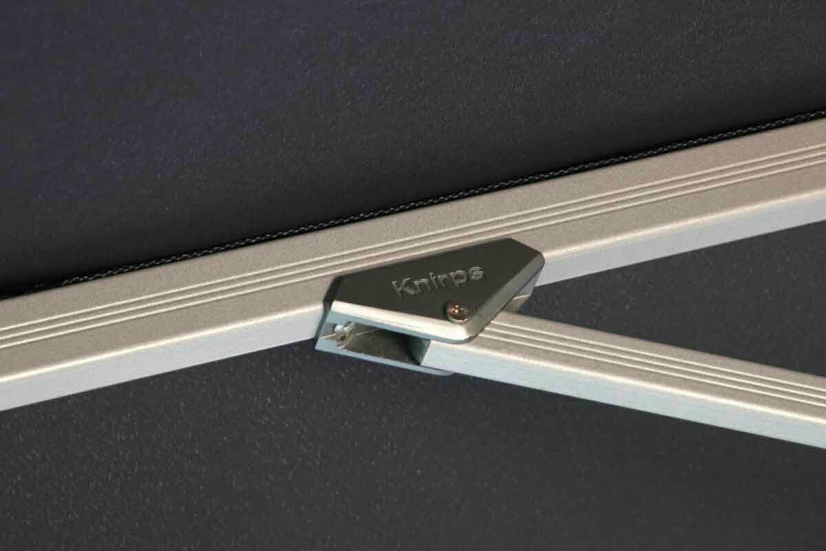 Nahaufnahme eines silbernen Metallrahmens mit der Aufschrift 'Knirps', Teil eines Pendelschirms.