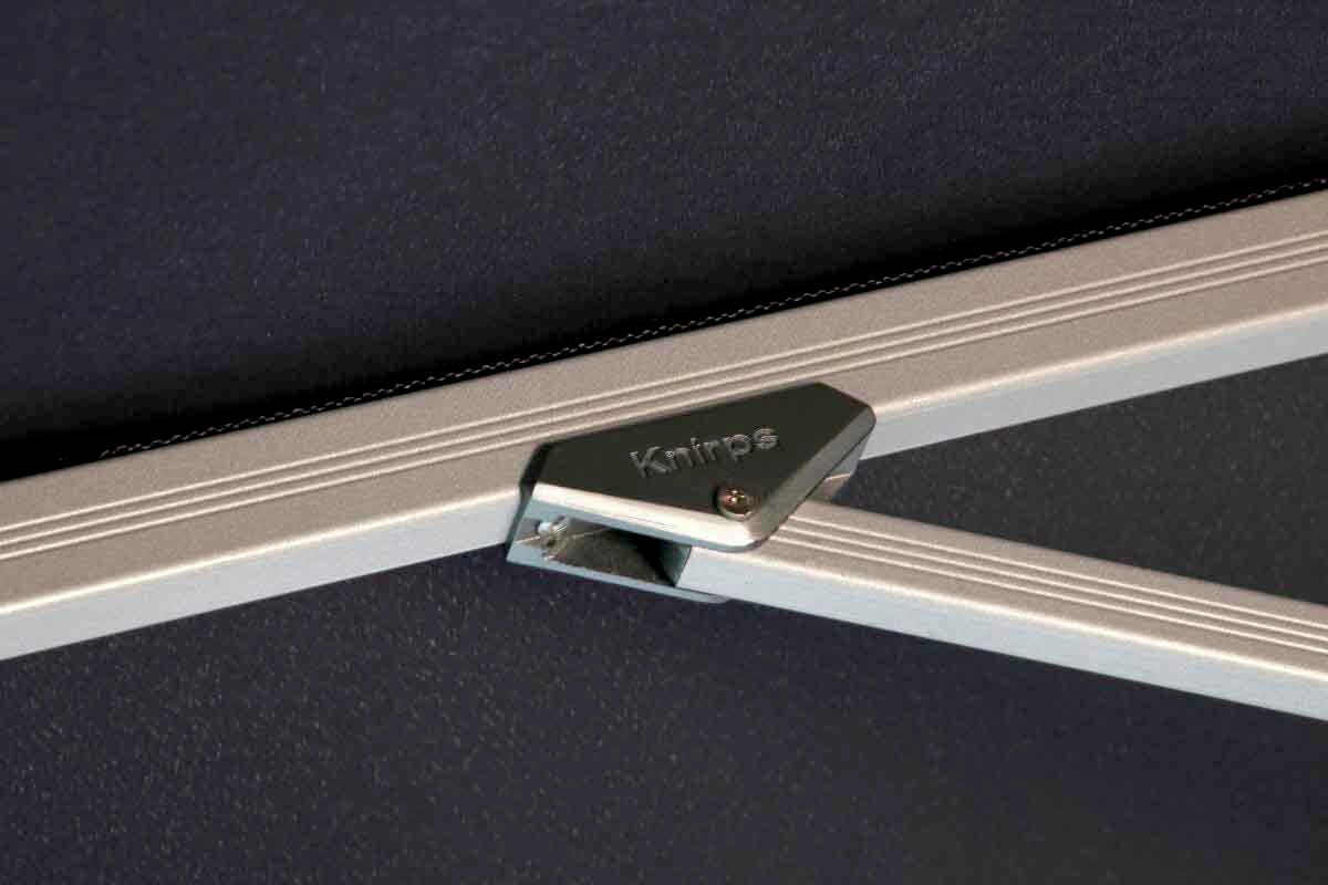 Nahaufnahme eines silbernen Metallrahmens mit der Aufschrift 'Knirps', Teil eines Pendelschirms.