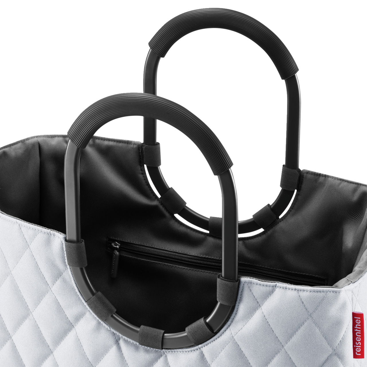 Nahaufnahme einer stilvollen Tasche mit schwarzem Innenfutter und zwei robusten, schwarzen Griffen. Die Außenseite zeigt ein elegantes Rautenmuster. Perspektive von oben.