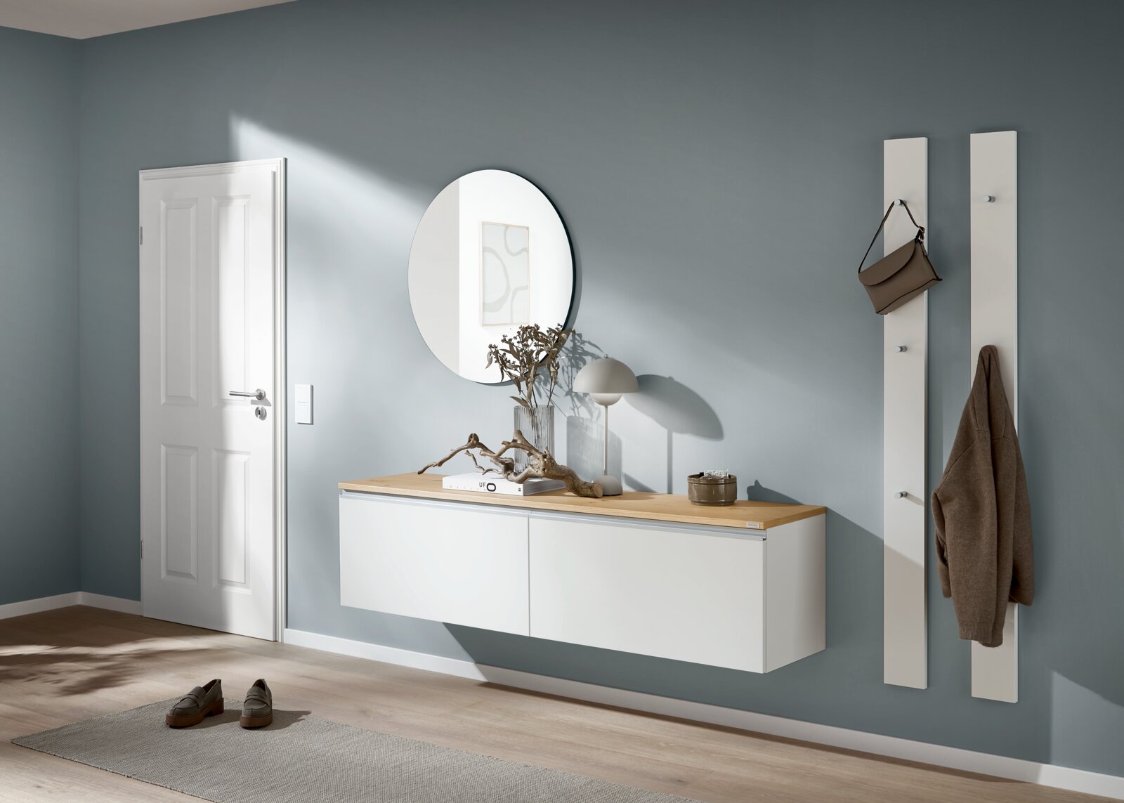Modernes Flur-Set mit schwebendem weißen Sideboard und Holzplatte, rundem Wandspiegel und zwei weißen Garderobenpaneelen mit Haken; Perspektive: frontale Ansicht auf Augenhöhe.