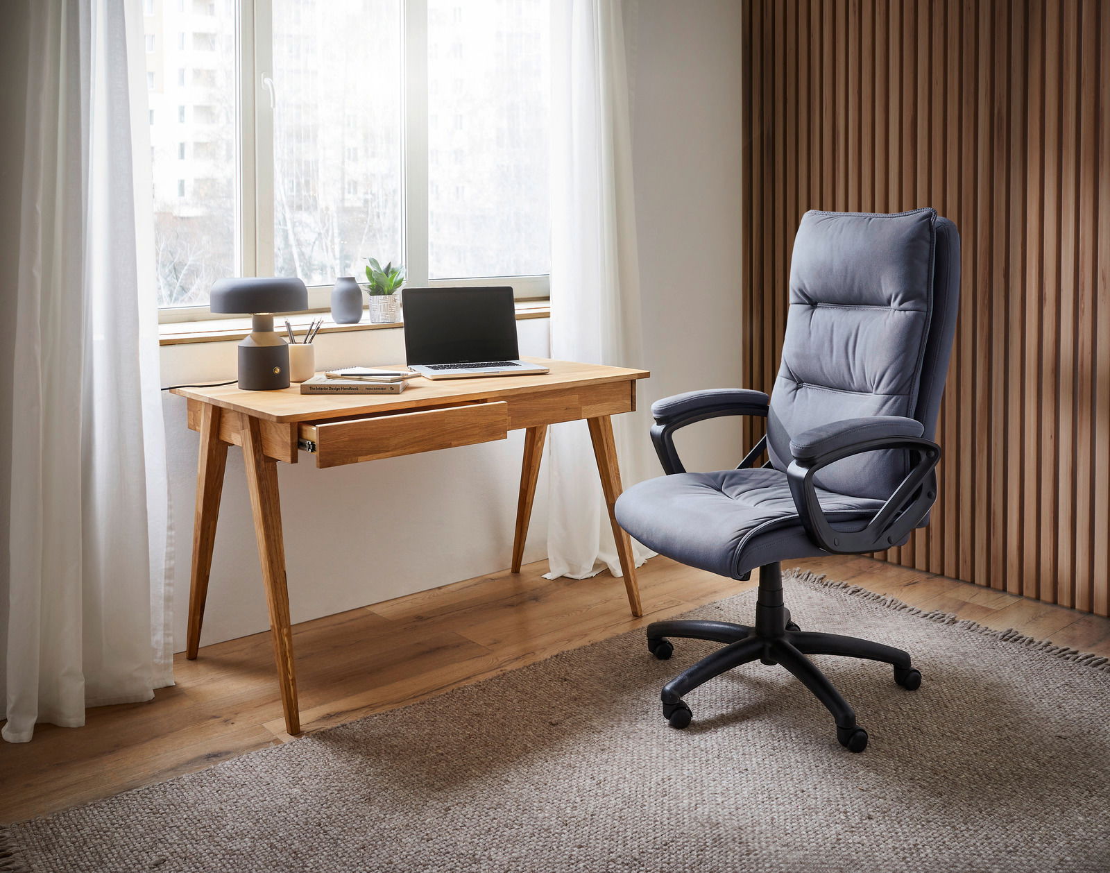 Moderner Schreibtisch aus Holz mit Laptop und Dekoration, seitliche Perspektive