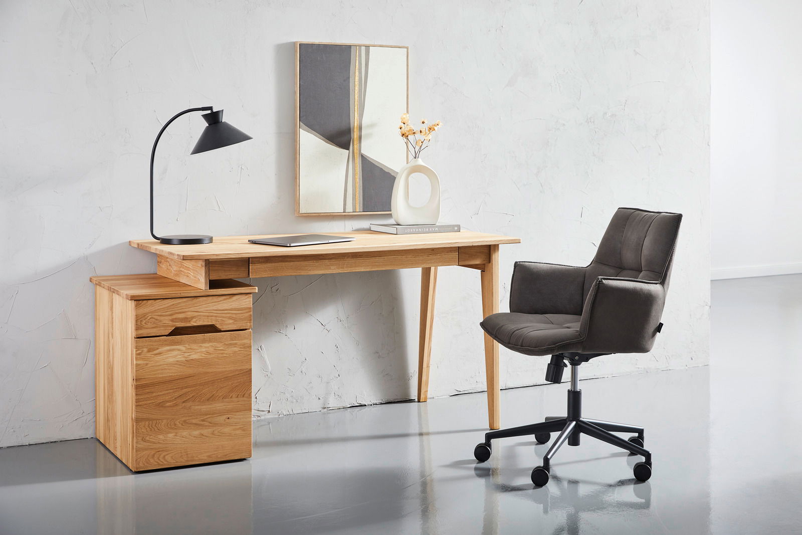 Moderner Drehsessel in dunklem Stoffbezug, seitliche Perspektive, neben einem Holztisch in einem minimalistischen Büro.