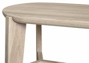 Nahaufnahme eines Sitzhockers aus hellem Holz mit abgerundeten Kanten, seitliche Perspektive.