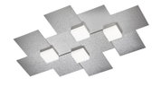 Moderne Deckenleuchte mit geometrisch angeordneten, gebürsteten Metallplatten und vier weißen, würfelförmigen Leuchtelementen, aus schräger Untersicht dargestellt