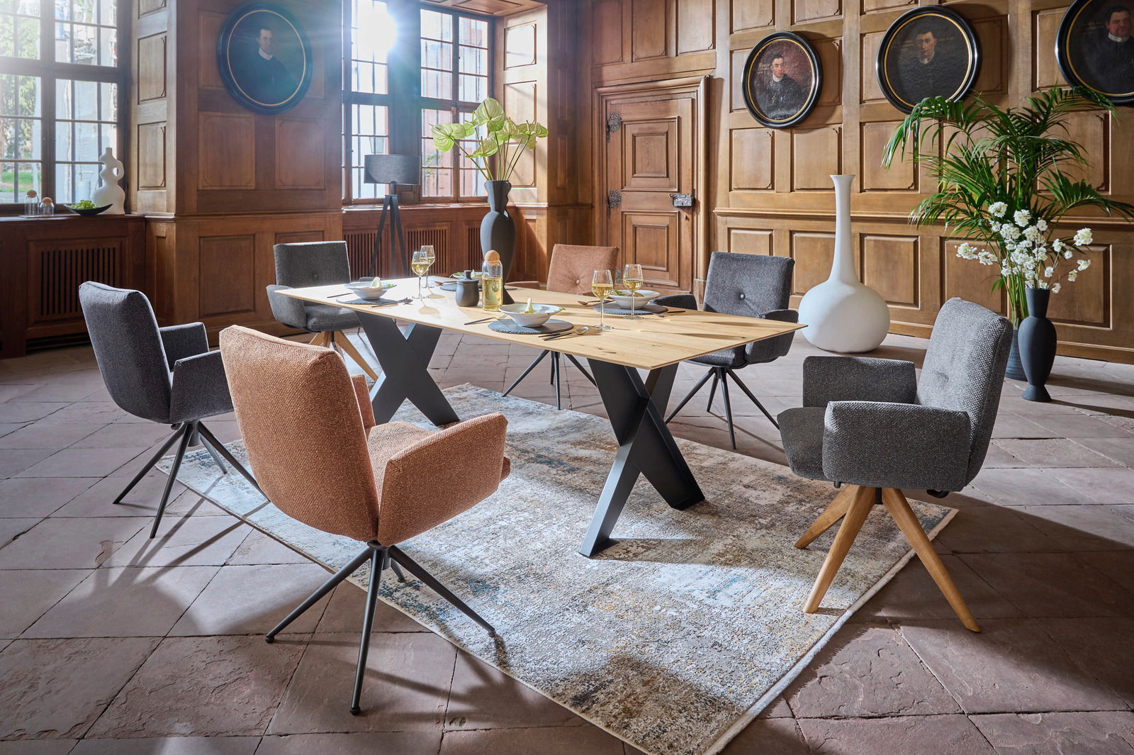 Dieter Knoll Esstisch COCOON Moderner Esstisch mit X-förmigen Beinen in einem eleganten Raum mit Holzwänden, umgeben von stilvollen Stühlen. Perspektive von schräg oben.