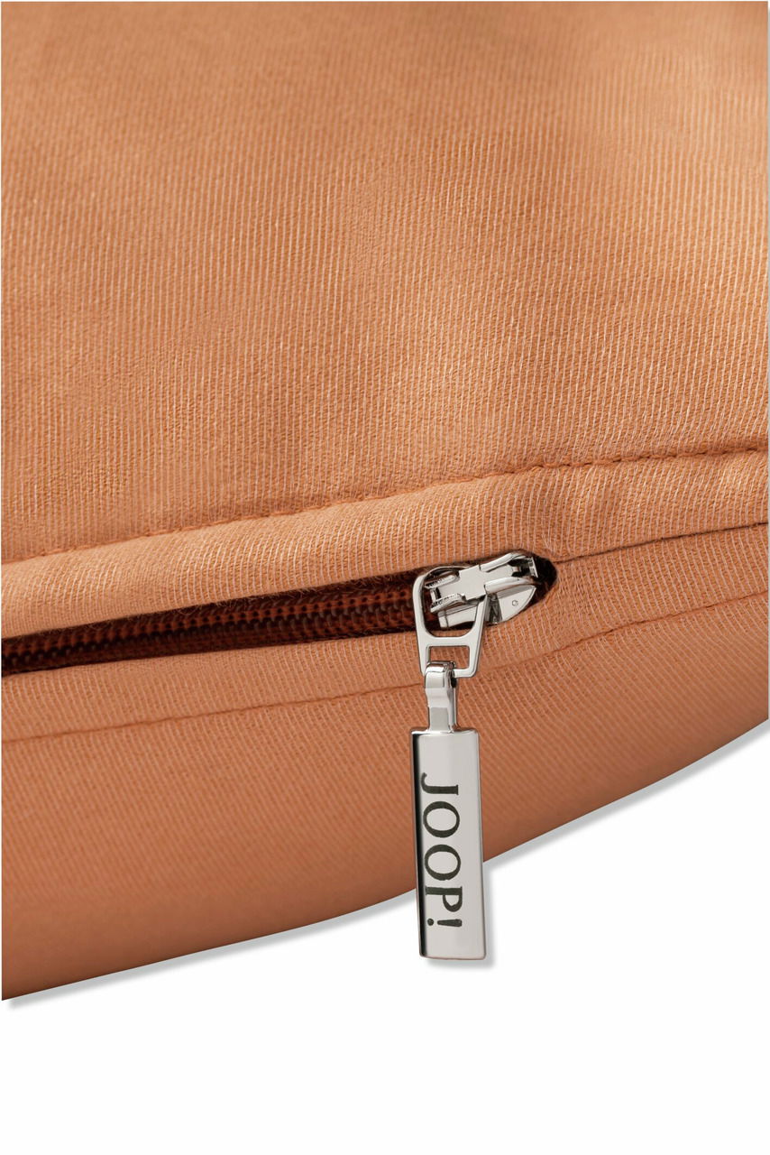 Nahaufnahme einer braunen Zierkissenhülle mit Reißverschluss und JOOP! Logo.