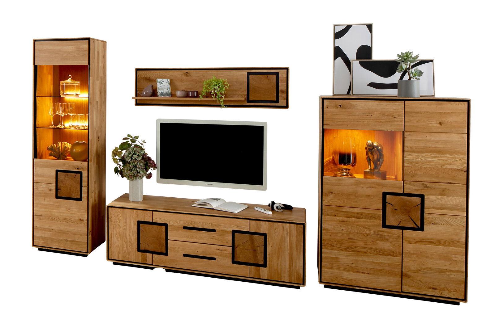 Wohnwand aus massivem Holz im modernen Design mit TV-Lowboard, Hängeregal, Vitrine und Highboard mit warm beleuchteten Glasfächern, Frontansicht leicht schräg vor weißem Hintergrund