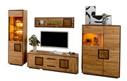 Wohnwand aus massivem Holz im modernen Design mit TV-Lowboard, Hängeregal, Vitrine und Highboard mit warm beleuchteten Glasfächern, Frontansicht leicht schräg vor weißem Hintergrund