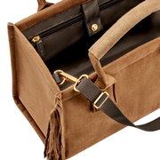 Detailfoto van een bruine suède handtas met franjes, zwarte voering, vak met ritssluiting en afneembare zwarte schouderriem met goudkleurige beslag, schuin van bovenaf gefotografeerd.