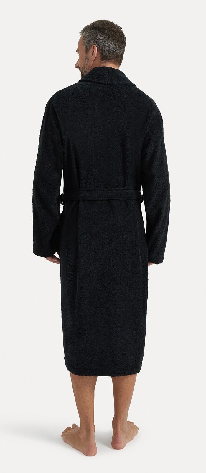 Rückansicht eines schwarzen Bademantels mit Schalkragen, getragen von einer Person. Der Bademantel hat einen Gürtel und reicht bis zu den Waden.