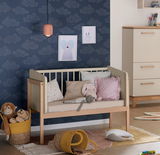 Anstellbett in einem Kinderzimmer, seitliche Perspektive, umgeben von Kissen und Spielzeug.