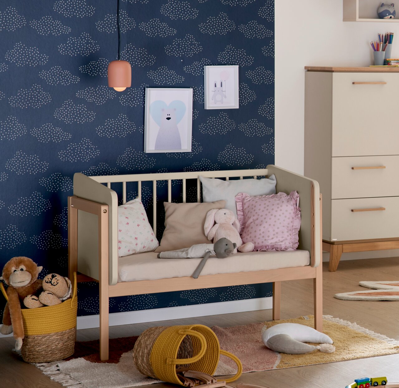 Anstellbett in einem Kinderzimmer, seitliche Perspektive, umgeben von Kissen und Spielzeug.