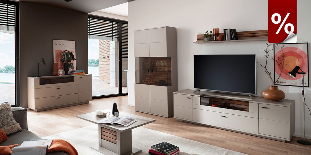 Modernes Wohnzimmer mit hellen Möbeln, TV-Wand, Sideboard und Couchtisch, große Fenster, Rabatt-Symbol.