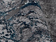 Nahaufnahme eines grauen Teppichs mit blauen und weißen Akzenten, perspektivisch von der Seite aufgenommen.