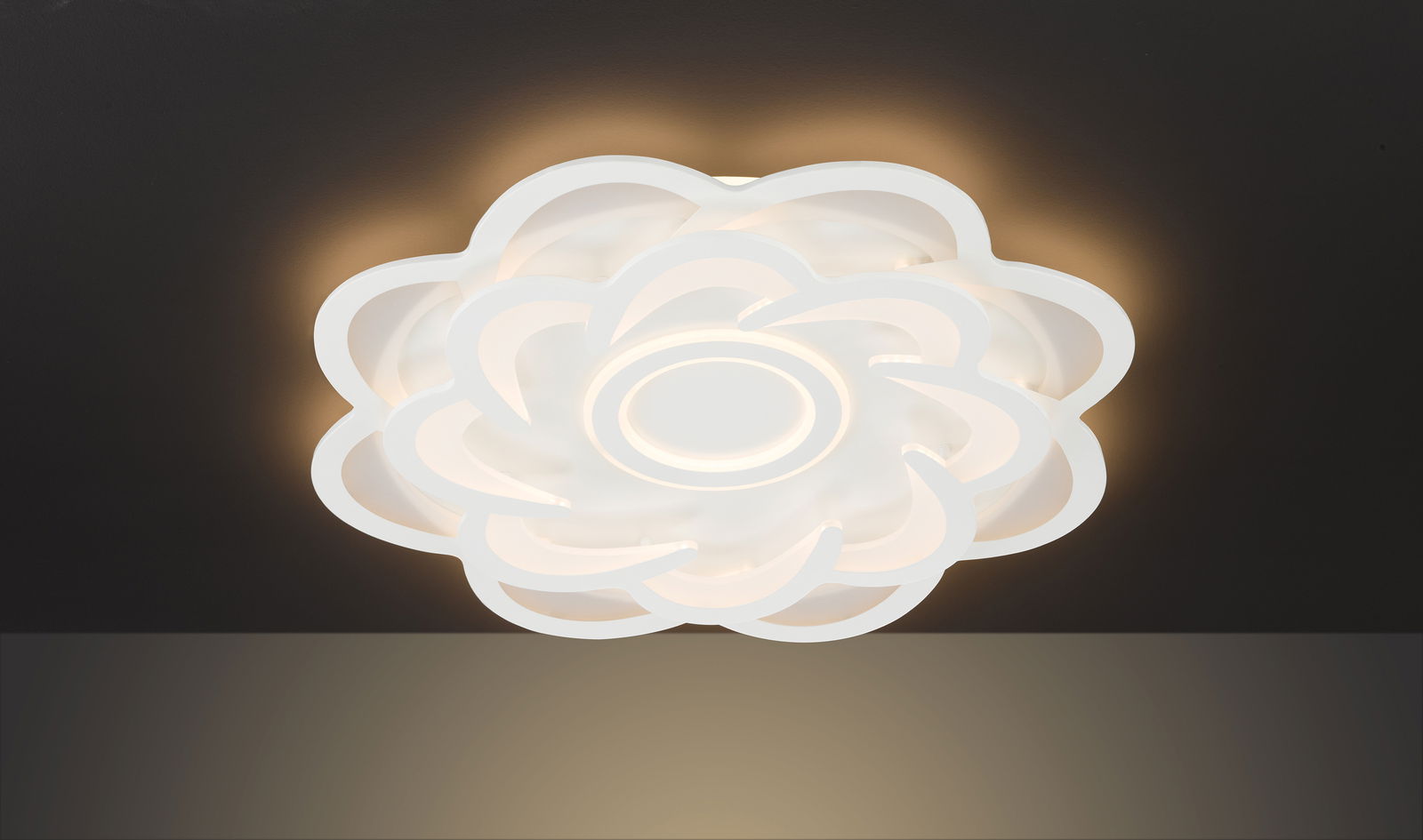 Moderne LED-Deckenleuchte in Blumenform, von unten betrachtet, mit warmweißem Lichtschein.