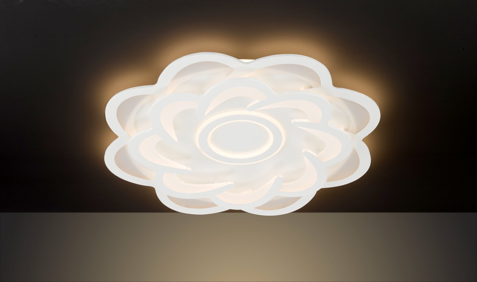 Moderne LED-Deckenleuchte in Blumenform, von unten betrachtet, mit warmweißem Lichtschein.