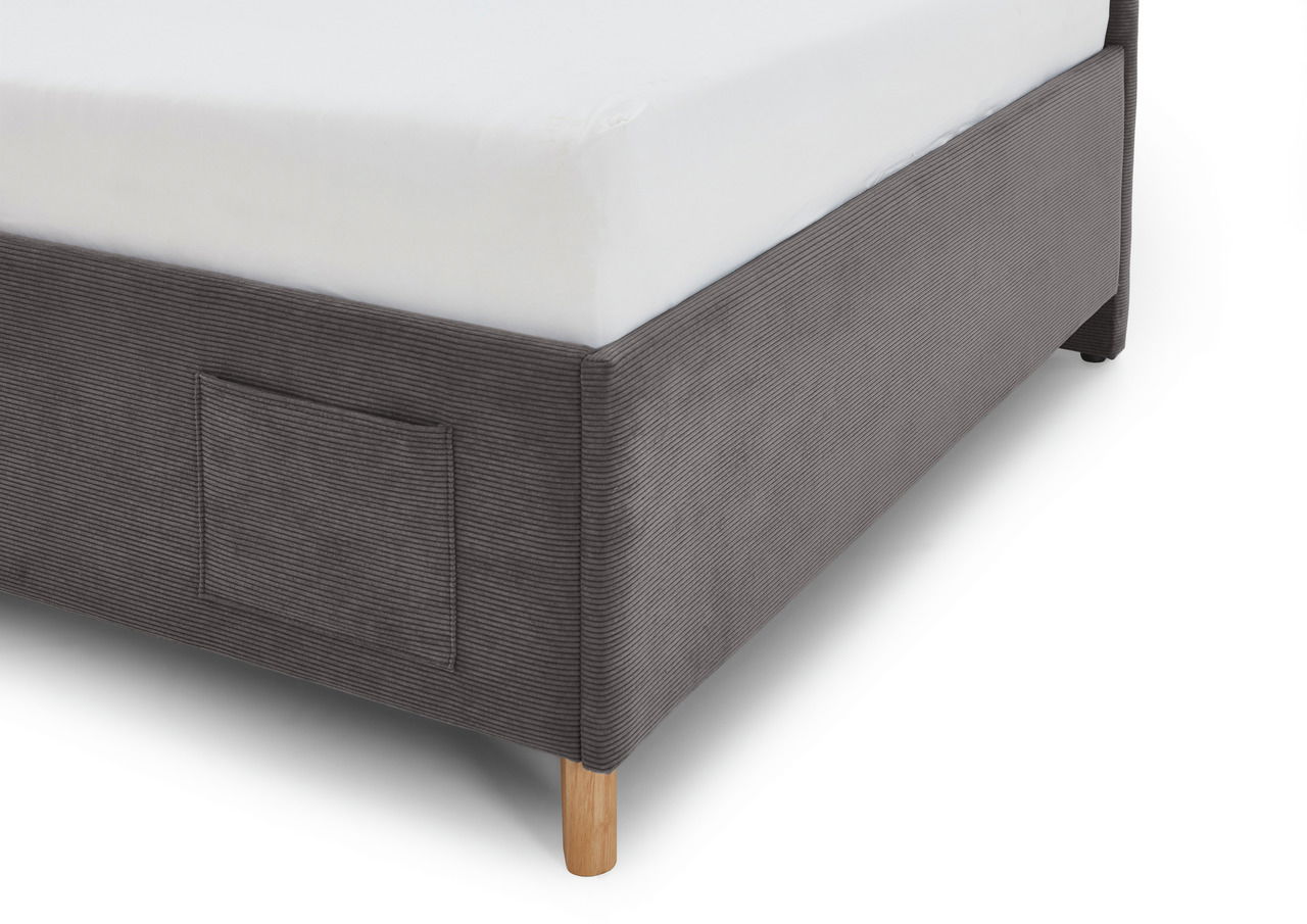 Nahaufnahme einer Polsterliege in grauem Stoff mit Holzfüßen, seitliche Perspektive