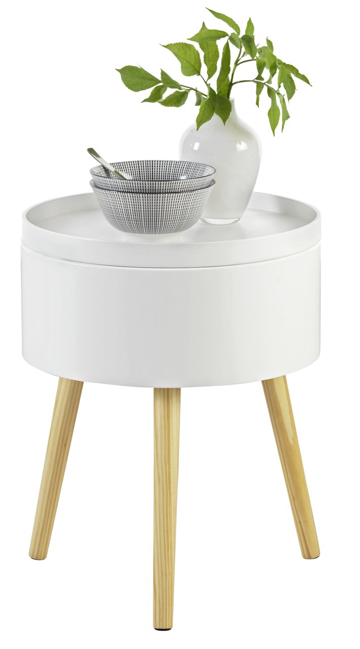 Weißer Beistelltisch mit runder Tischplatte und hellen Holzbeinen, darauf eine weiße Vase mit grünen Blättern und eine Schale mit Löffel, aus der Perspektive von vorne.