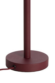 Nahaufnahme eines weinroten Lampenfußes mit rundem Sockel und Kabel, seitliche Perspektive.