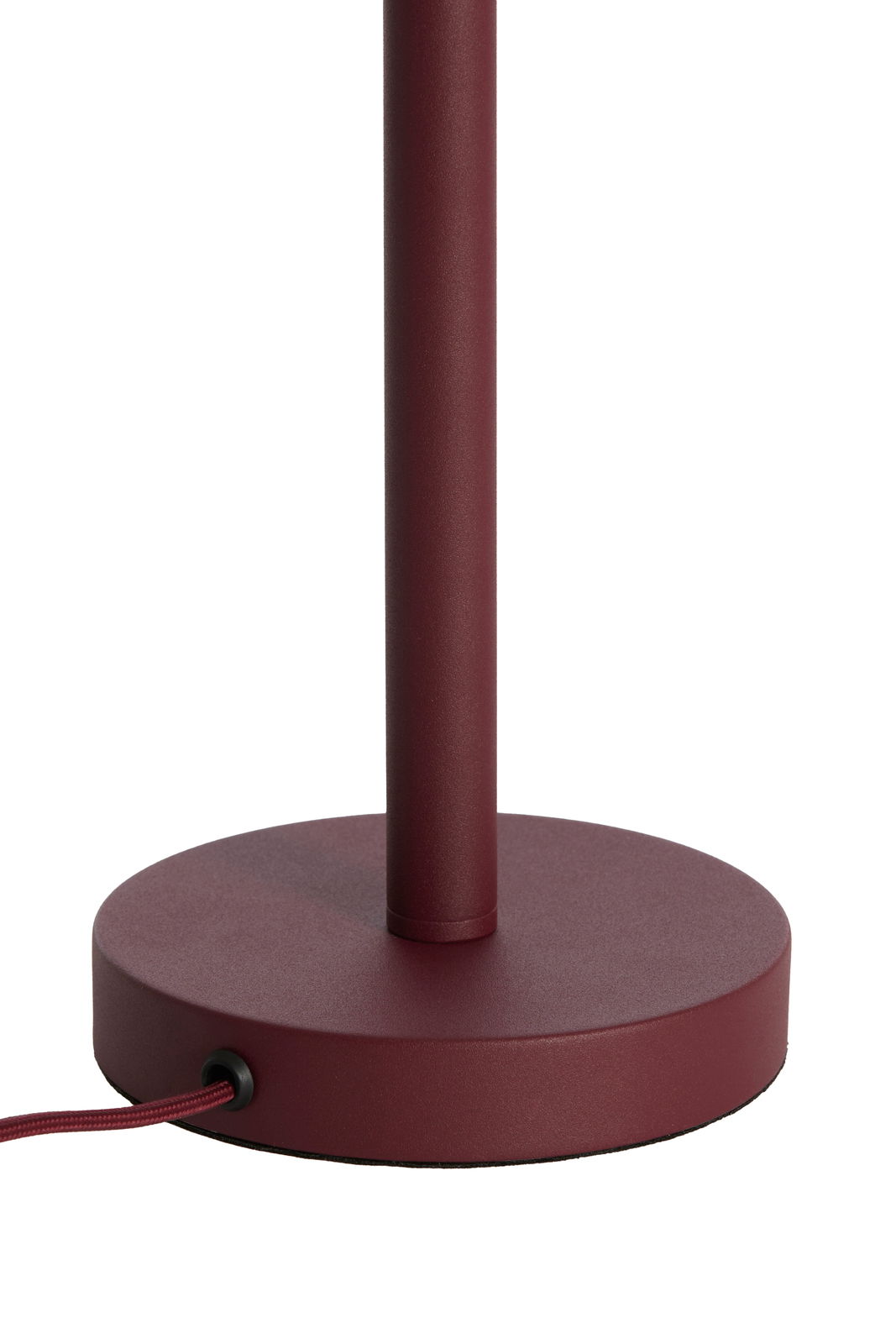 Nahaufnahme eines weinroten Lampenfußes mit rundem Sockel und Kabel, seitliche Perspektive.