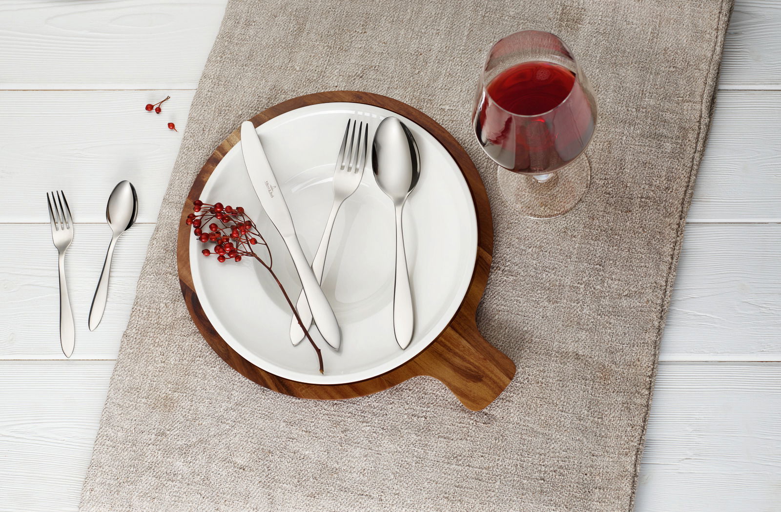 Villeroy & Boch Besteck Arthur 30-tlg. ARTHUR Besteckset Arthur 30-tlg. auf einem gedeckten Tisch mit Teller, Glas Rotwein und Dekoration aus roten Beeren, von oben betrachtet.