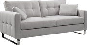 Hellgraues 2-Sitzer-Sofa mit gepolsterter, gesteppten Rückenlehne, zwei Kissen und verchromten Kufenfüßen, in schräger Frontansicht von links freigestellt auf weißem Hintergrund.