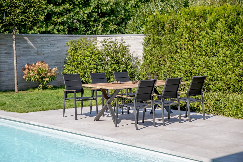 Niehoff-Garden Sessel REVENT Gartenmöbel-Set mit sechs schwarzen Stühlen und einem Holztisch auf einer Terrasse am Pool, seitliche Perspektive