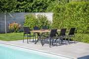 Gartenmöbel-Set mit sechs schwarzen Stühlen und einem Holztisch auf einer Terrasse am Pool, seitliche Perspektive