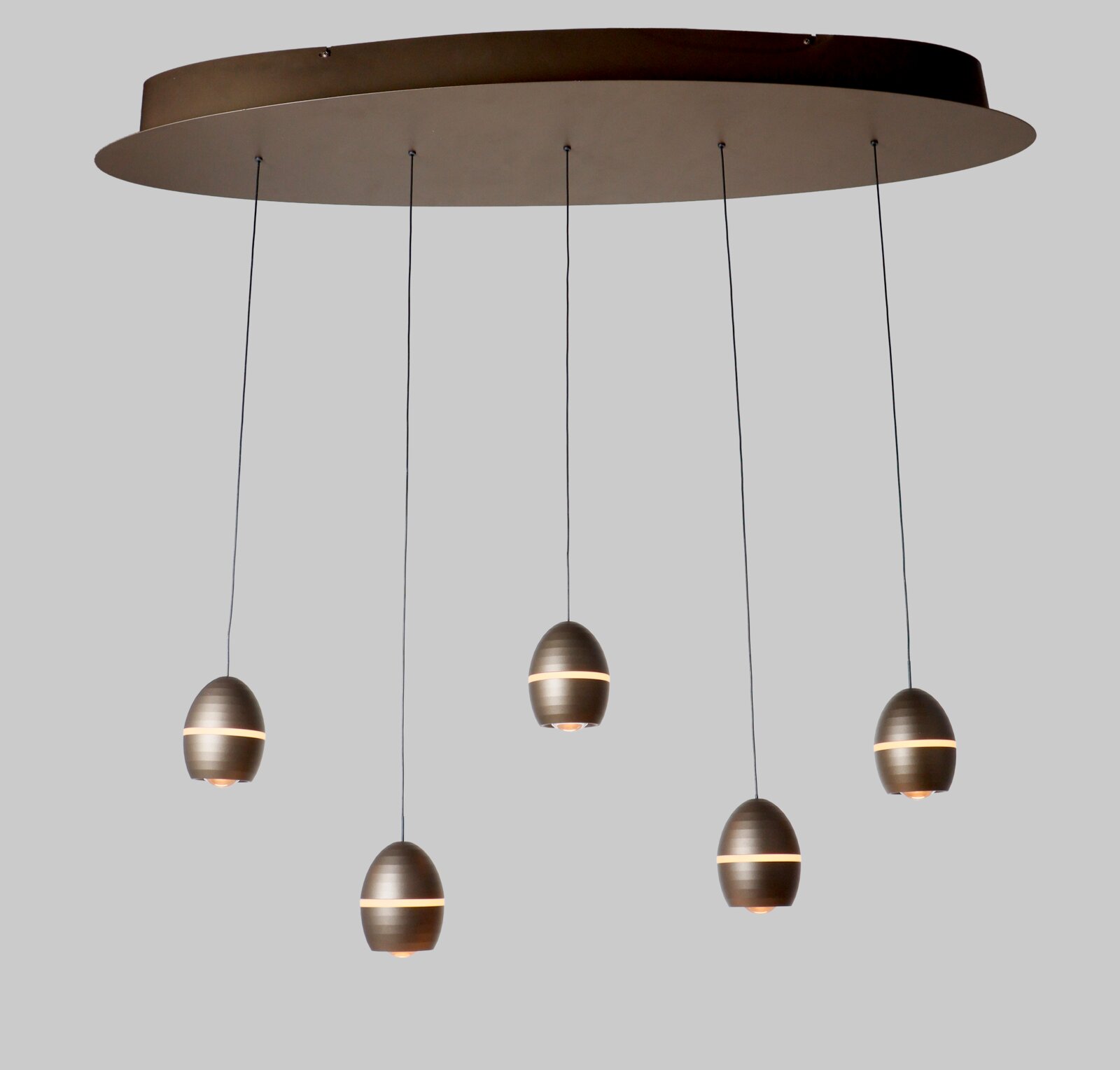 TRIO SELECT LED-hanglamp BEDFORD Moderne hanglamp met grote ronde plafondplaat en vijf eivormige metalen pendels in bronskleur met warme lichtband, schuin van onderen gefotografeerd