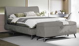 Graues Boxspringbett 180x200 mit Bettbank im Vordergrund, seitliche Perspektive