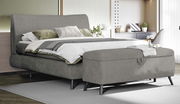 Graues Boxspringbett 180x200 mit Bettbank im Vordergrund, seitliche Perspektive