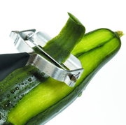 Nahaufnahme eines Sparschälers 'Universale', der eine Gurke schält. Der Sparschäler hat eine Metallklinge und einen schwarzen Griff.