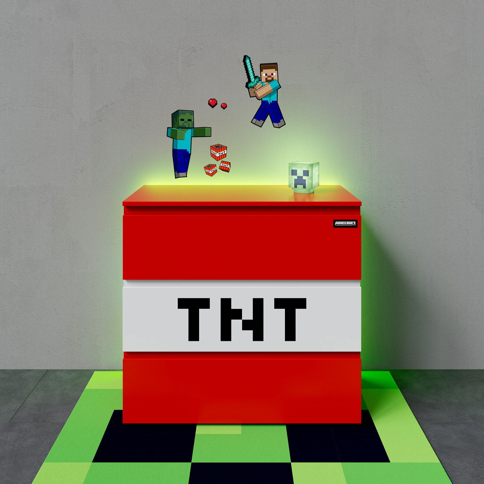 Minecraft-inspirierte TNT-Box als Deko- oder Aufbewahrungsbox in Rot-Weiß mit großem „TNT“-Schriftzug, oben mit schwebenden Pixel-Figuren (Steve, Zombie) und Creeper-Kopf, frontal aus leicht erhöhter Perspektive vor grauer Wand auf grün-schwarzem Pixelbod