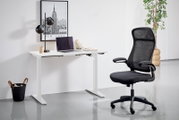 Moderner E-Schreibtisch in Weiß mit schwarzem Bürostuhl, seitliche Perspektive. Der Schreibtisch ist mit einer Lampe, einem Laptop und Schreibutensilien dekoriert. Im Hintergrund ein New York Poster und eine Pflanze.