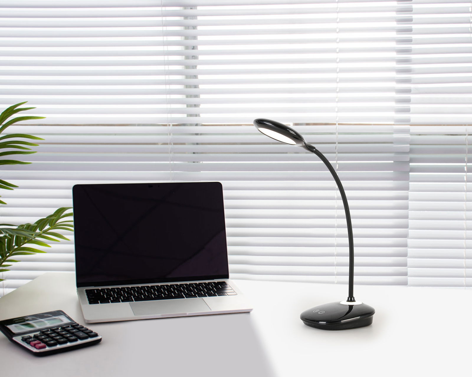 LED-Schreibtischleuchte auf einem Schreibtisch neben einem Laptop und einem Taschenrechner, seitliche Perspektive