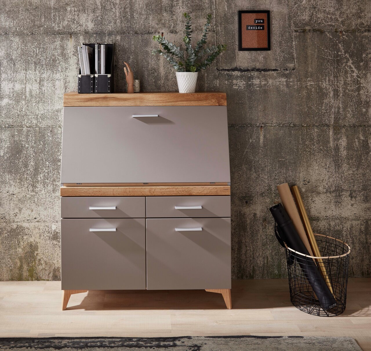 Moderner Sekretär aus Holz und Metall mit Schubladen und Klappe, frontal fotografiert, dekoriert mit Pflanzen und Büromaterial.