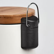 Nahaufnahme eines Kosmetikeimers mit Holzdeckel und schwarzem Griff, seitliche Perspektive