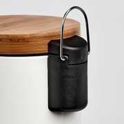 Nahaufnahme eines Kosmetikeimers mit Holzdeckel und schwarzem Griff, seitliche Perspektive