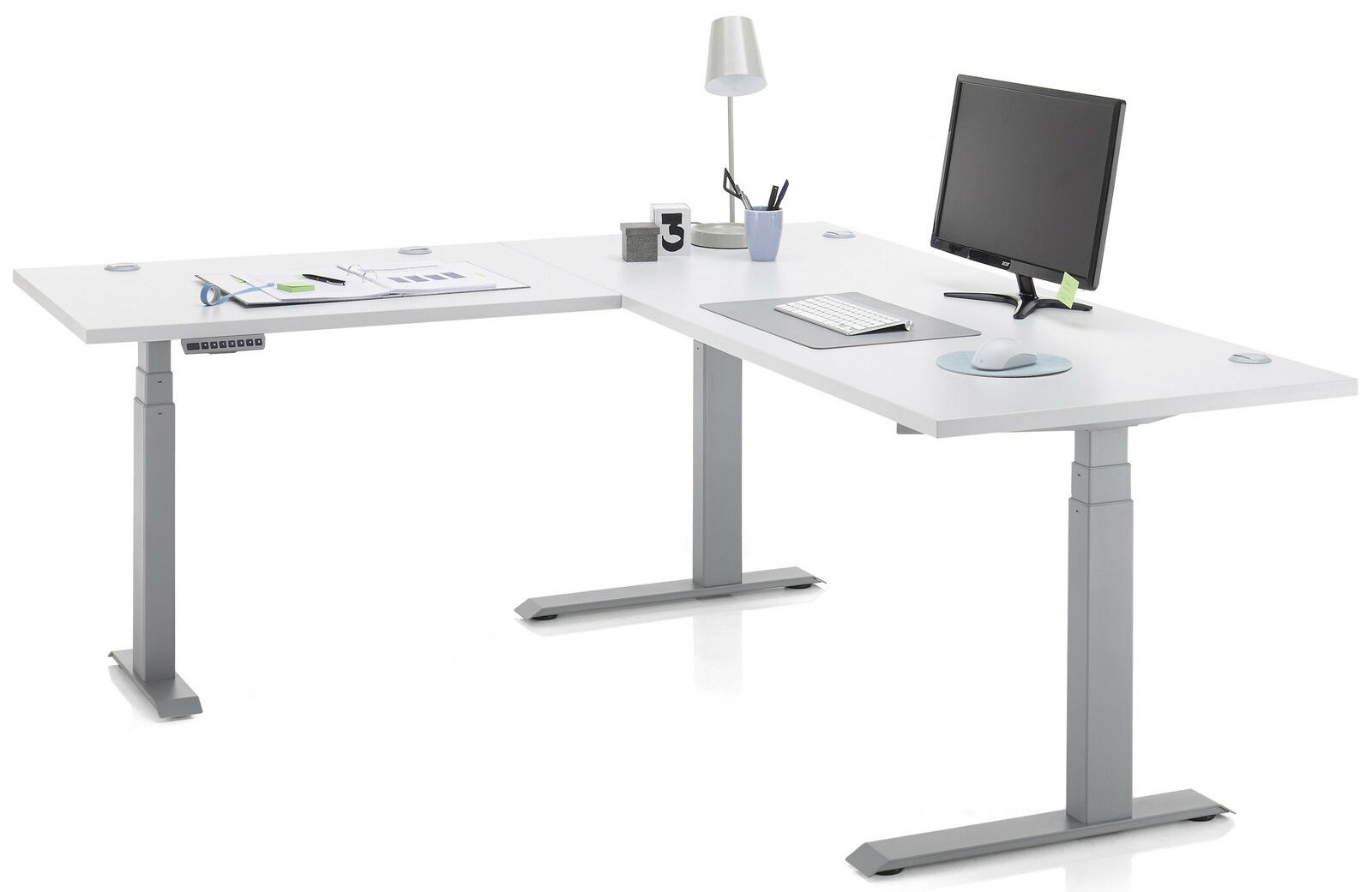 Moderner weißer E-Eckschreibtisch mit höhenverstellbaren Beinen, ausgestattet mit Monitor, Tastatur, Maus und Schreibtischlampe, aus seitlicher Perspektive.