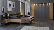 Modernes Schlafzimmer mit Holz- und Grautönen, bestehend aus einem Bett mit integrierten Nachttischen, dekorativen Kissen und einem großen Kleiderschrank, seitliche Perspektive.
