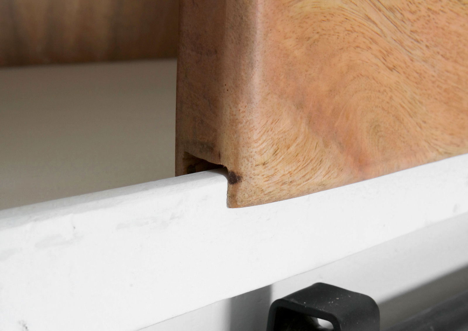 Nahaufnahme einer Ecke einer Vitrine mit Holz- und Metallelementen, seitliche Perspektive.